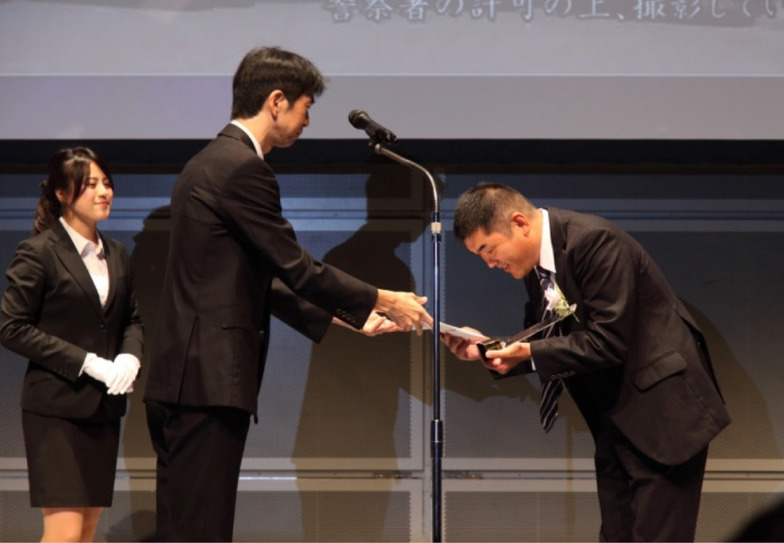 総務省・飯村博之地域放送推進室長(左)と グランプリ受賞の京丹波町ケーブルテレビ 西村美貴氏