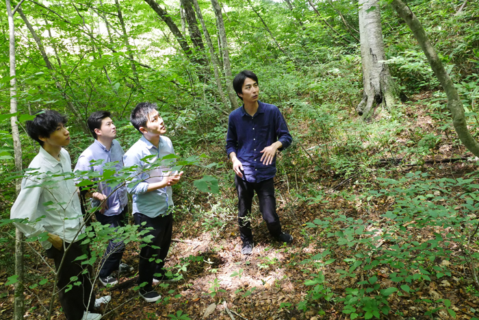 矢野建築設計事務所のメンバーを森に案内するヒダクマの松本氏（右）